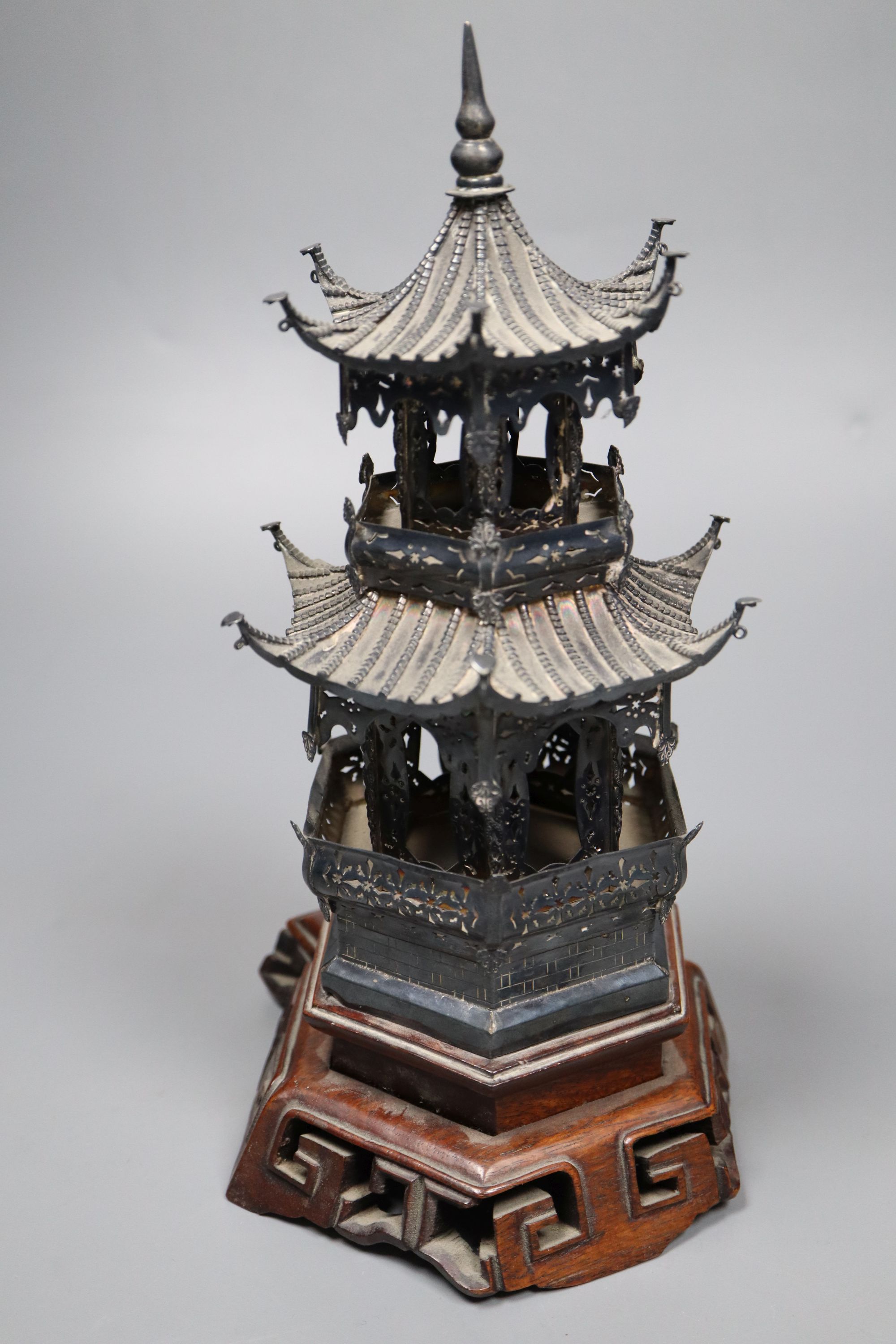 An early 20th century Chinese white metal miniature model of a pagoda, on a hardwood base, model 21.4cm, 11.5oz,